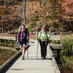 Women hiking across a bridge at Pandapas Pond